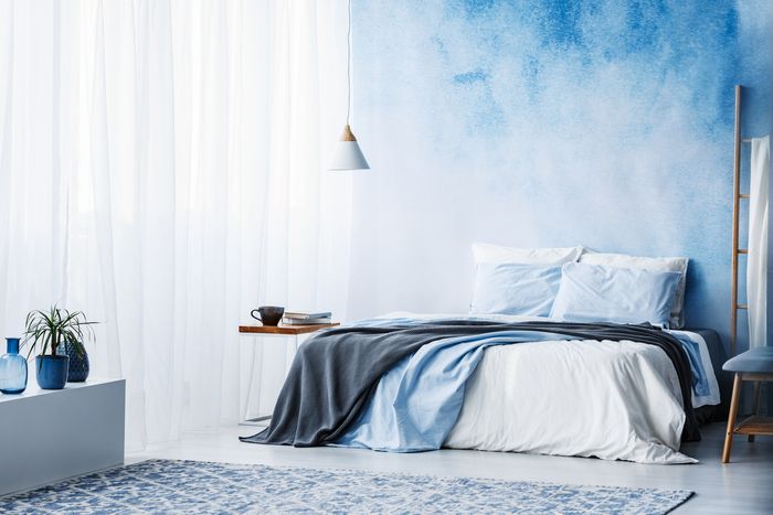 A bedroom with blue walls, blue carpet, and a blue comforter on a large bed.